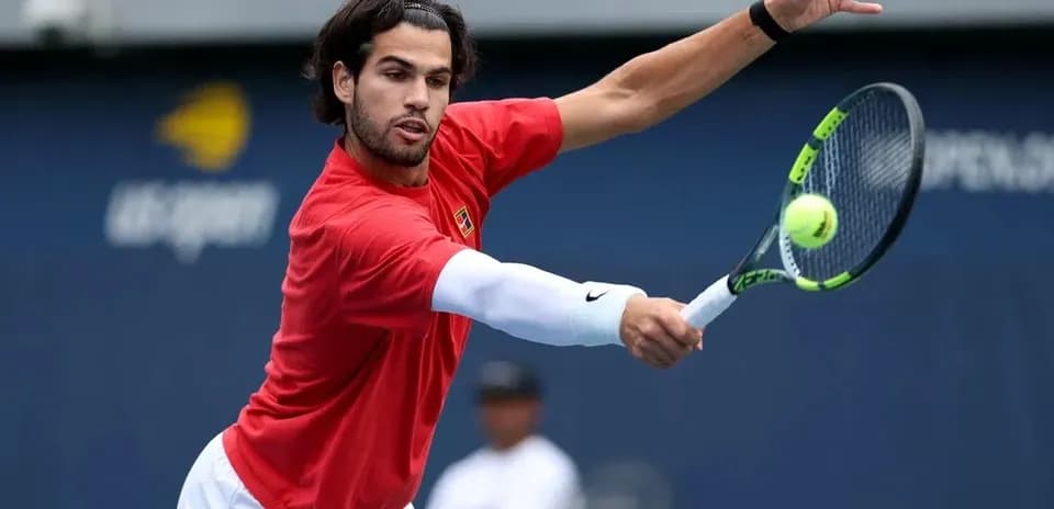 Jugador de tenis golpeando una pelota en la cancha