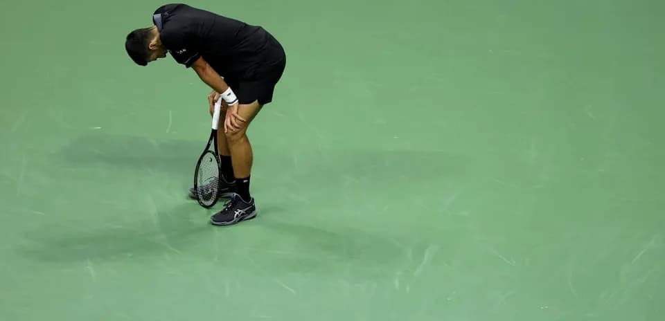 Jugador de tenis con raqueta, mostrando agotamiento