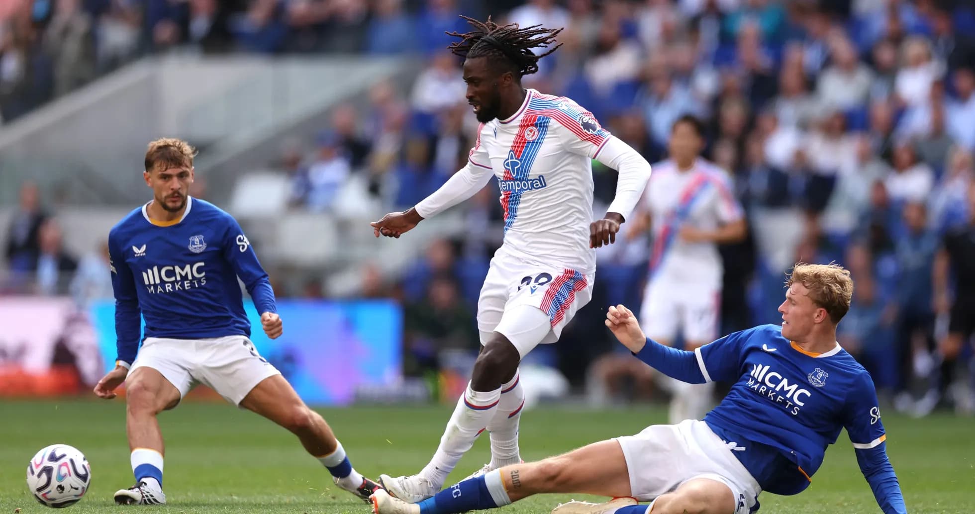 Jugador driblando mientras dos oponentes caen al suelo
