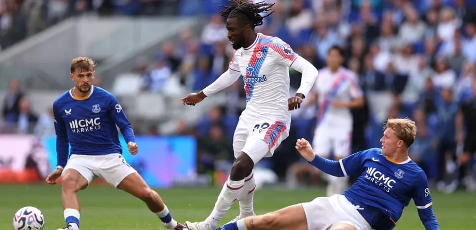 Jugador driblando mientras dos oponentes caen al suelo