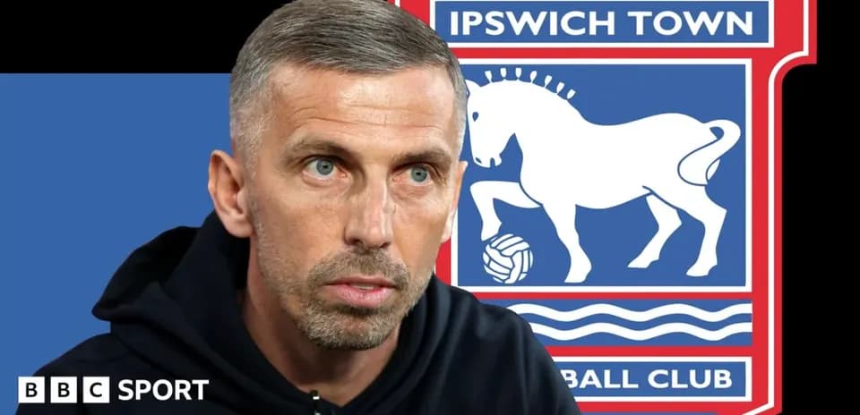 Entrenador hablando frente al logo de Ipswich Town