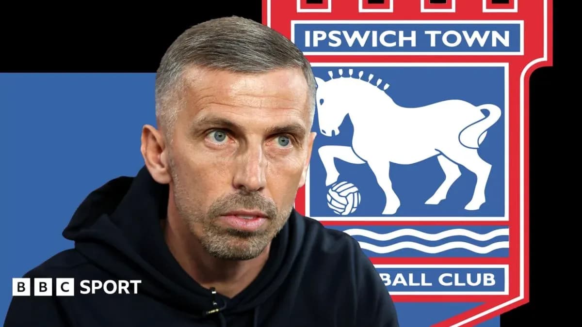 Entrenador hablando frente al logo de Ipswich Town