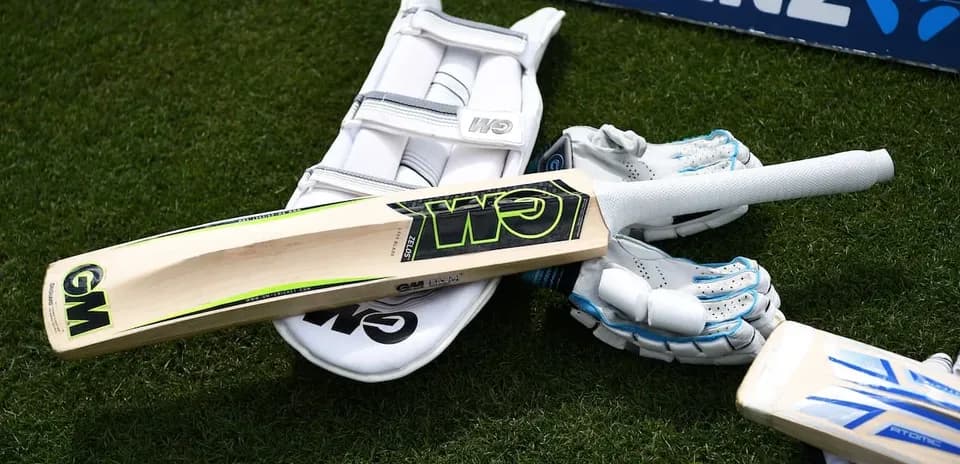 Bate de cricket y guantes sobre césped