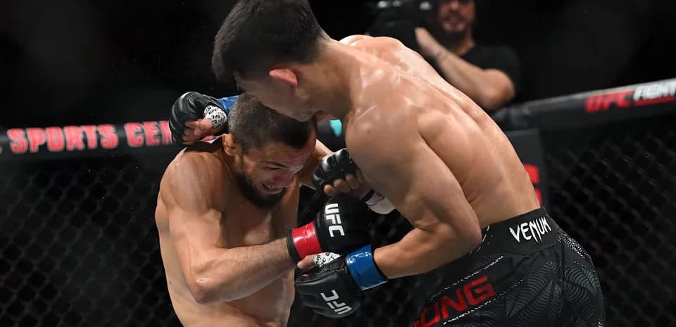 Luchadores de MMA intercambiando golpes en el octágono