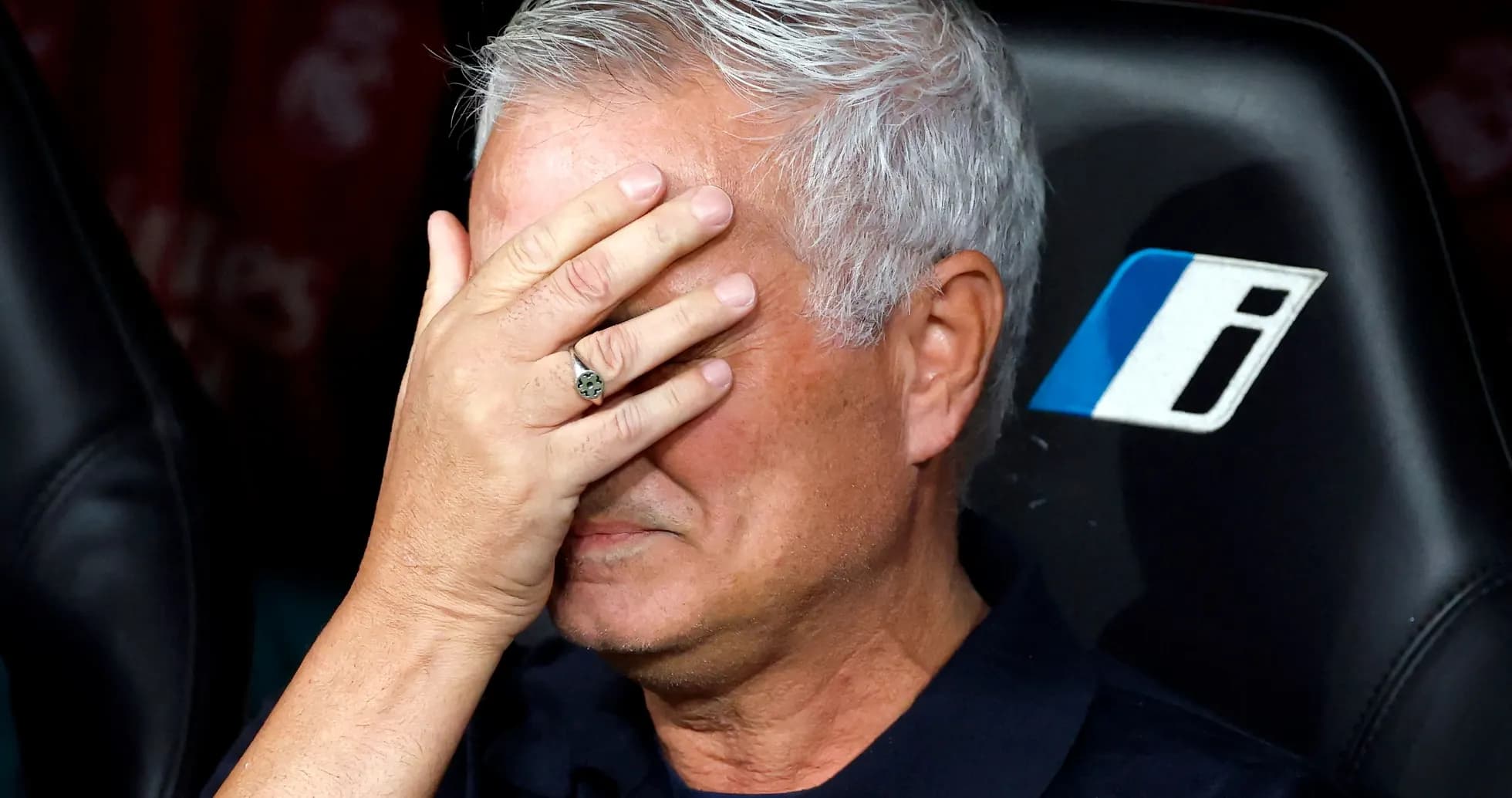 Entrenador cubriendo su rostro con la mano en el banquillo