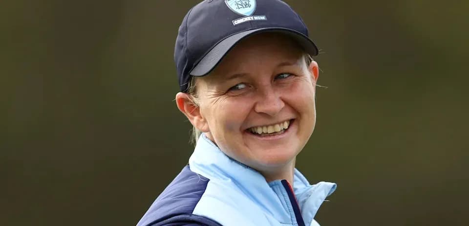 Jugadora de cricket sonriendo en el campo