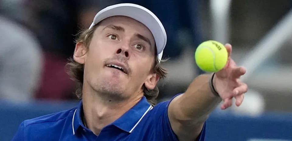 Jugador lanzando la pelota durante un saque de tenis