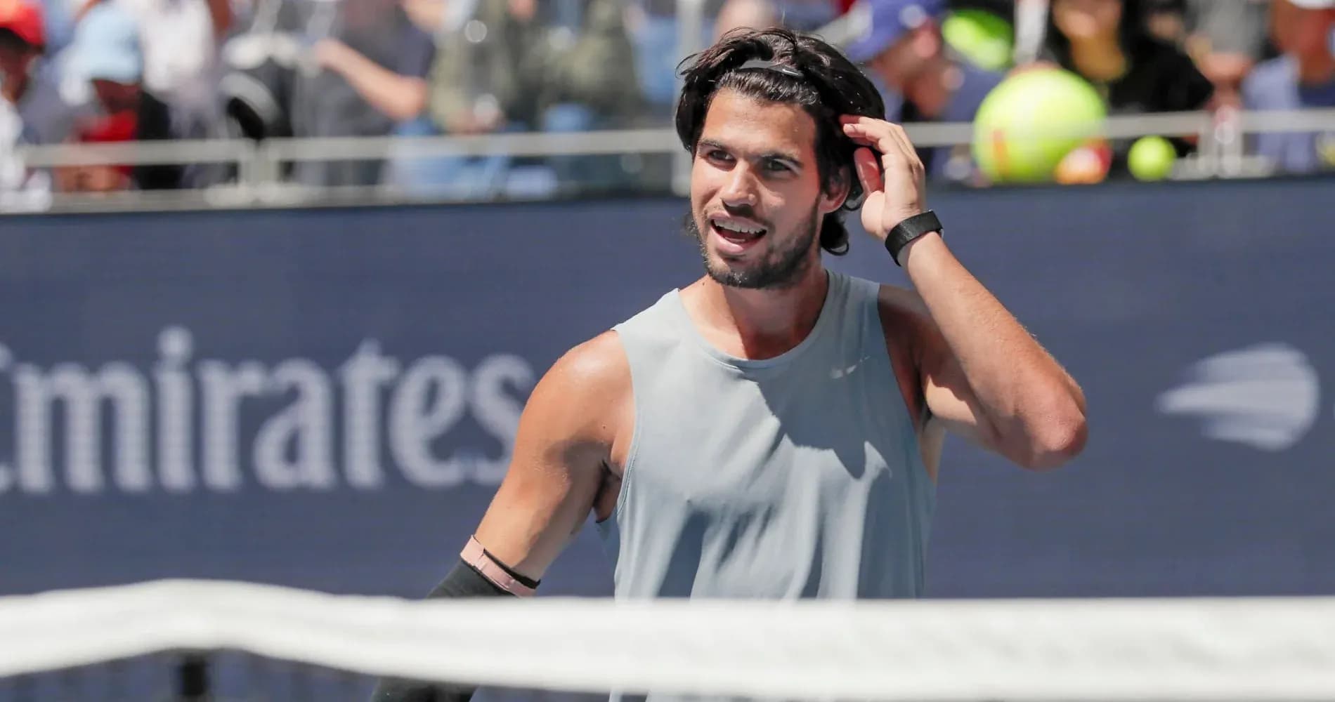 Jugador de tenis ajustando su cabello en la cancha