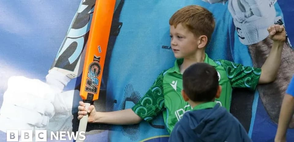 Niño sosteniendo un bate de cricket junto a un mural