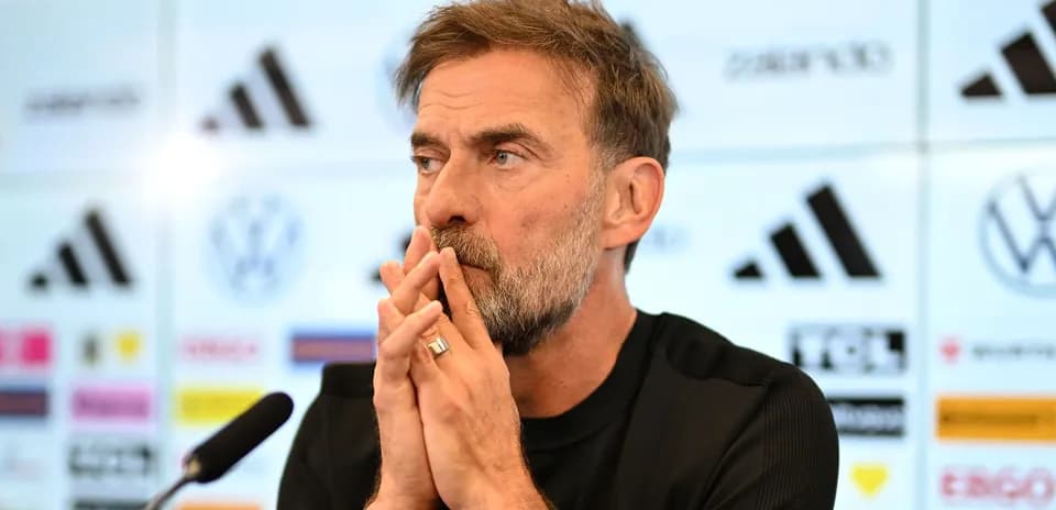 Entrenador en conferencia de prensa con manos entrelazadas