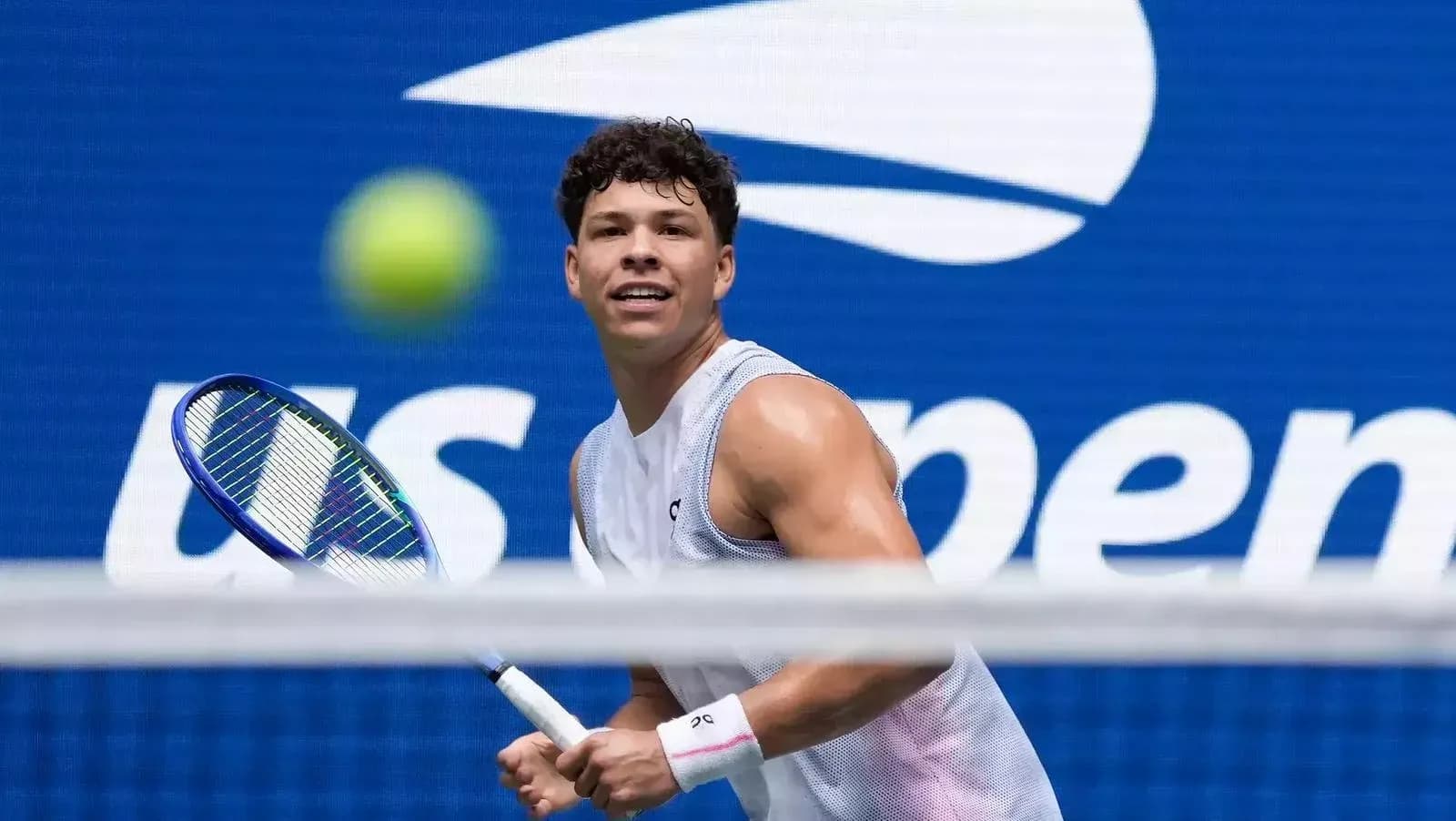 Jugador de tenis en acción con logo del US Open