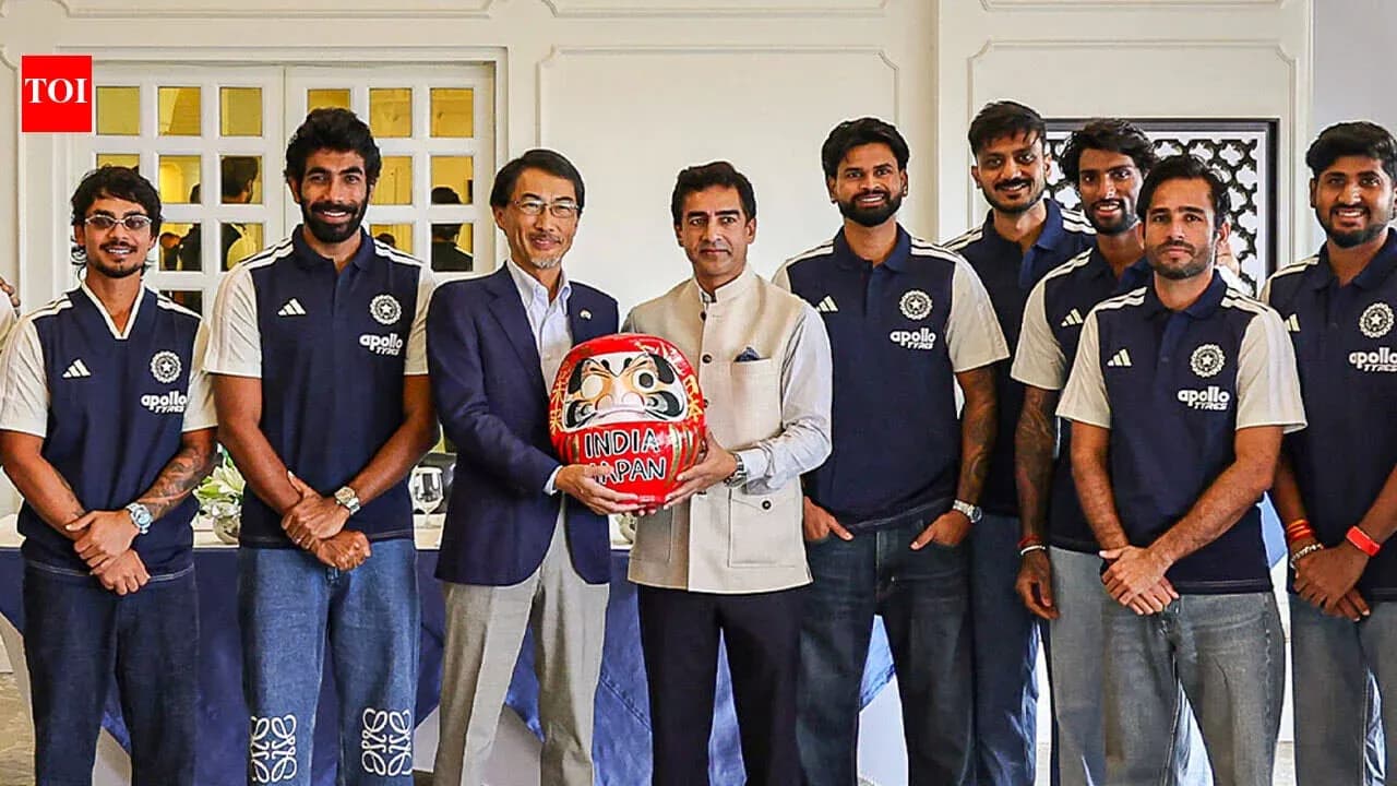 Equipo de cricket posando con figura de Daruma