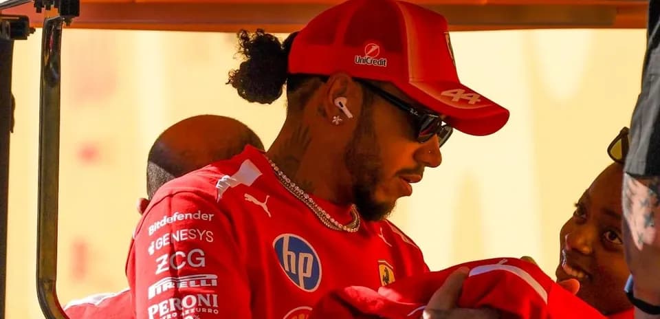 Lewis Hamilton con gorra de Ferrari interactuando con persona