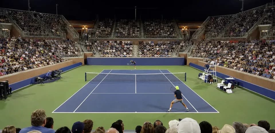 Partido de tenis bajo las luces con público en las gradas