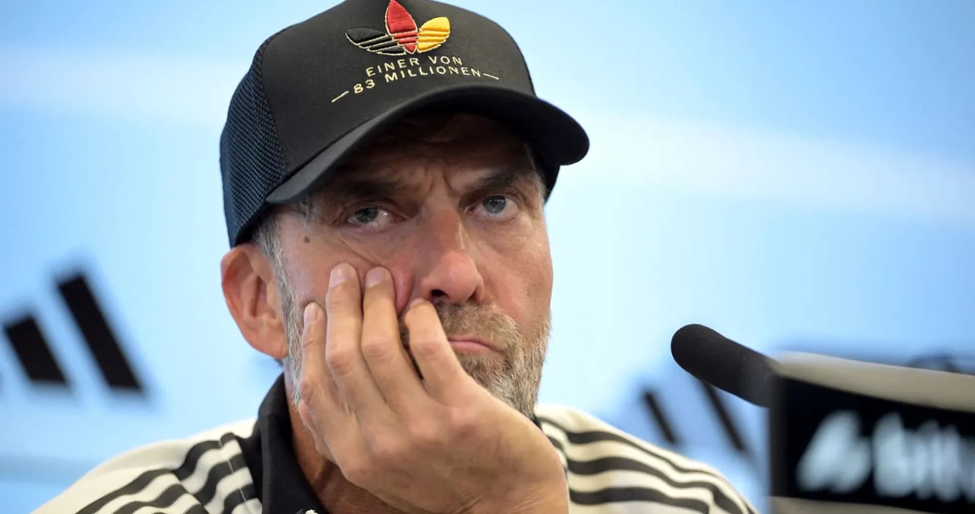 Entrenador en conferencia de prensa con gesto pensativo