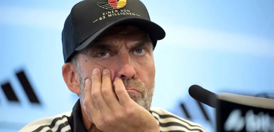 Entrenador en conferencia de prensa con gesto pensativo