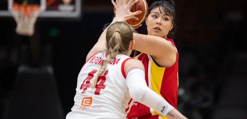 Jugadora lanzando el balón durante un partido de baloncesto