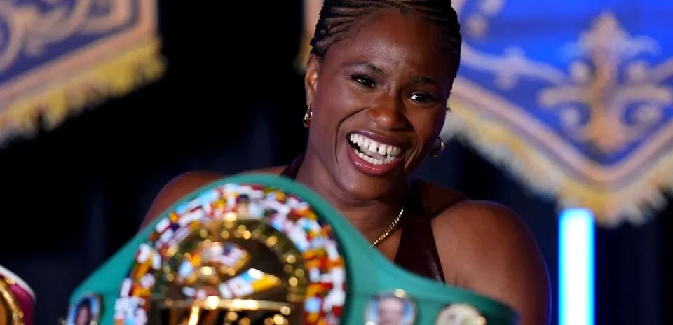 Boxeadora sosteniendo cinturón de campeona con sonrisa