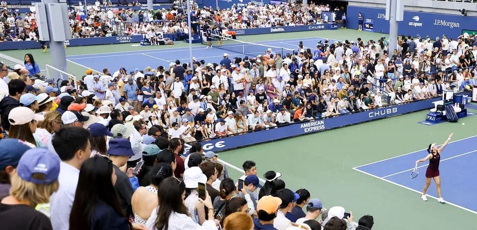 Jugadora sirviendo en un partido de tenis con público