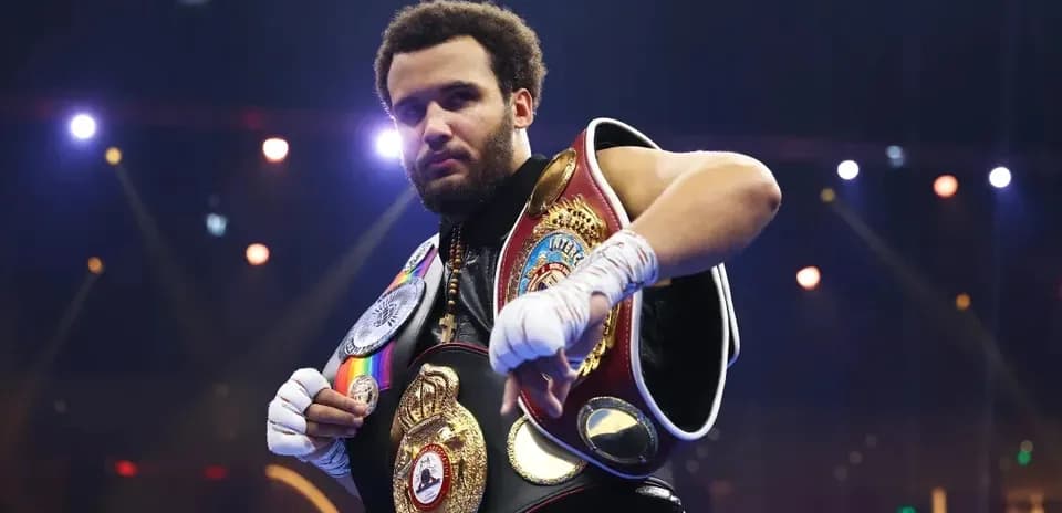 Boxeador mostrando cinturones de campeón en el ring