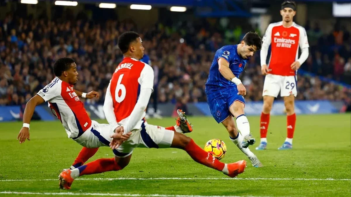 Jugador de Chelsea disparando mientras dos defensores de Arsenal intentan bloquear
