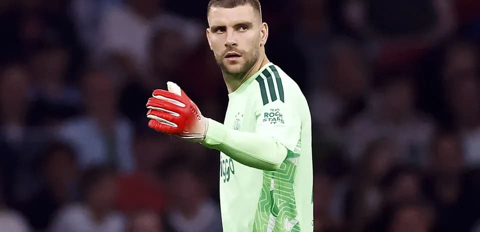 Portero con guantes rojos señalando durante el partido