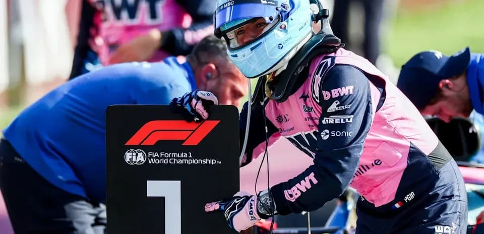 Piloto de F1 señalando el número uno en el garaje