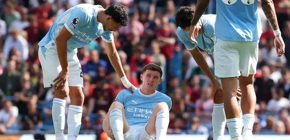 Jugador de Manchester City sentado en el campo con compañeros