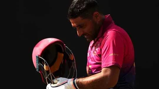 Jugador de cricket sosteniendo su casco en el campo