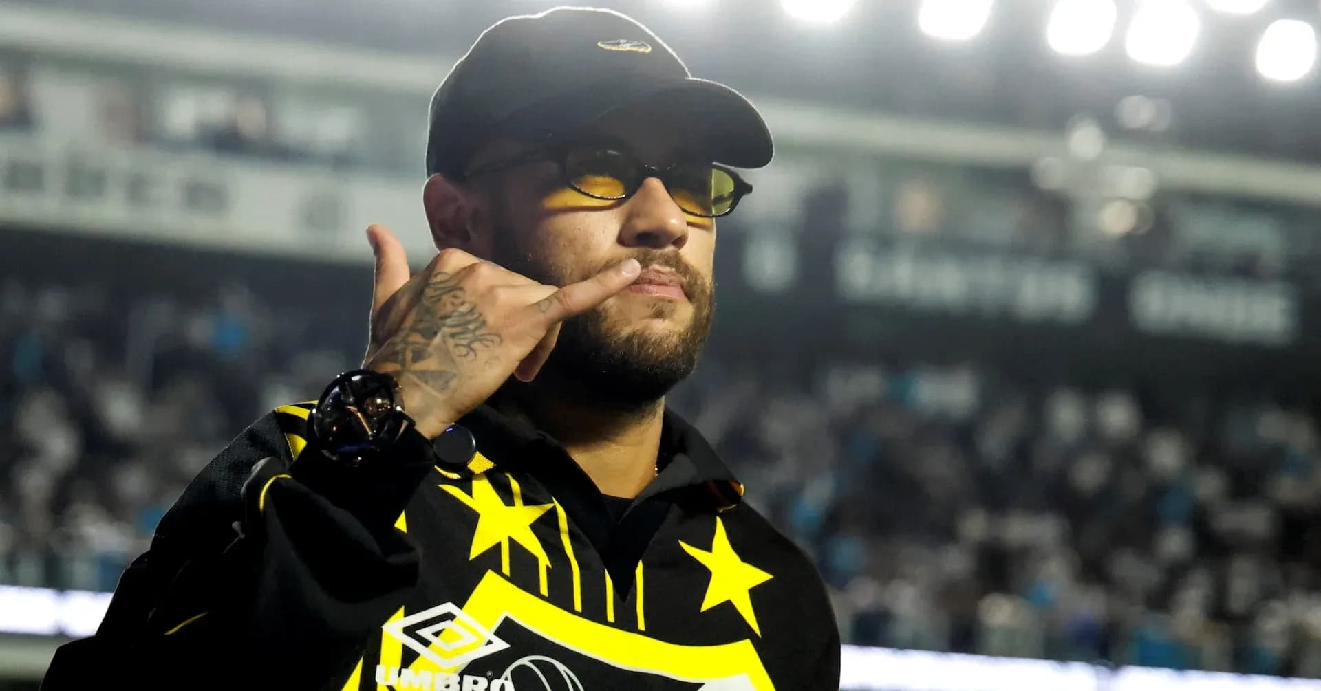Persona con gafas y gesto de llamada en estadio