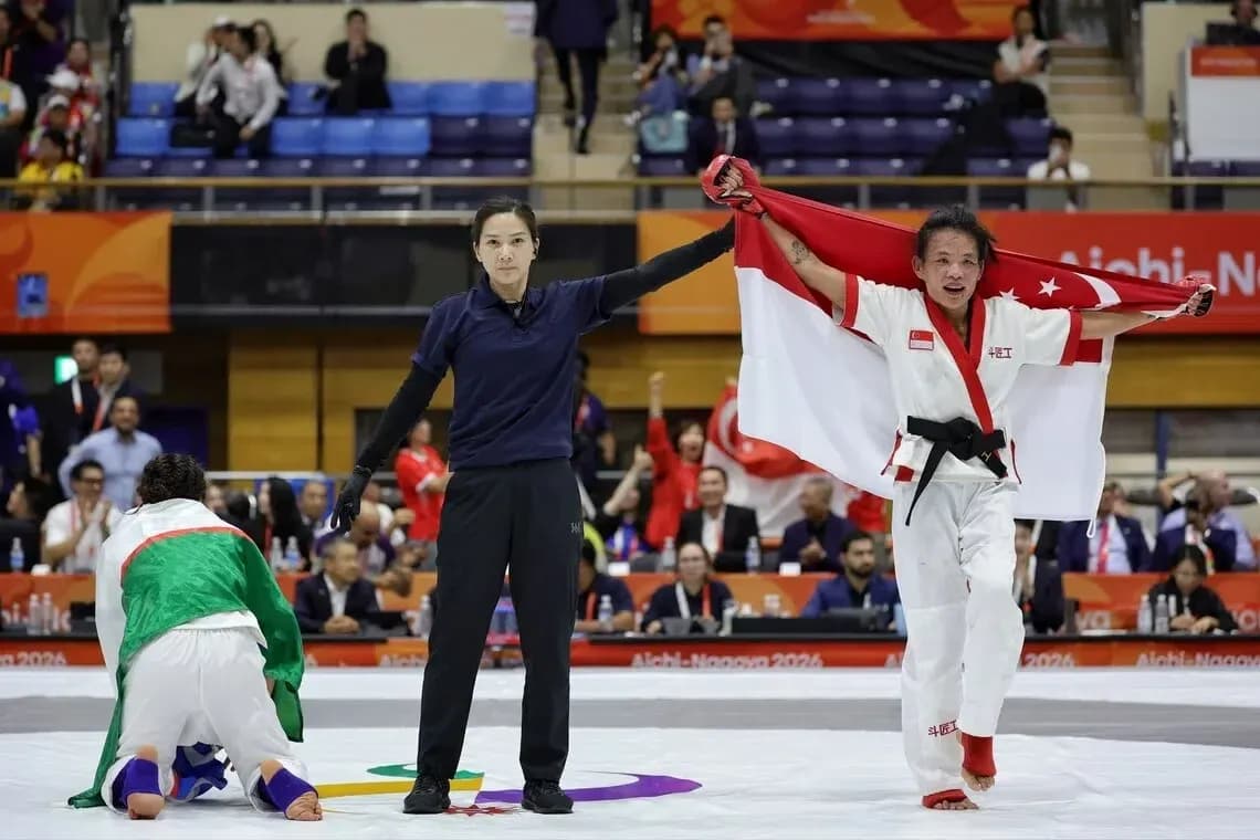 Competidor sosteniendo bandera de Singapur tras victoria