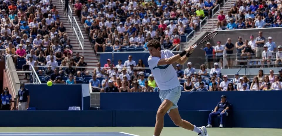 Jugador golpeando la pelota en partido de tenis
