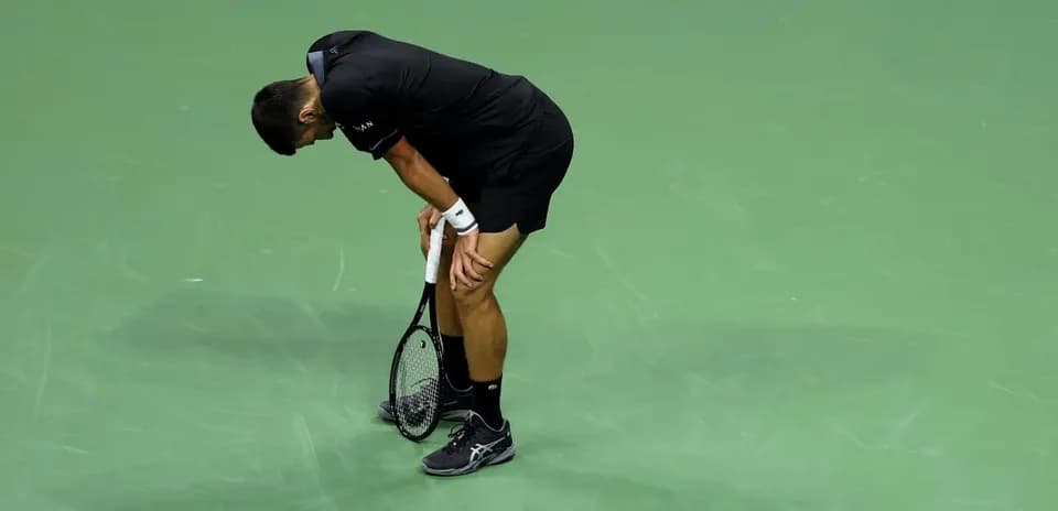 Jugador de tenis agachado con raqueta en la mano