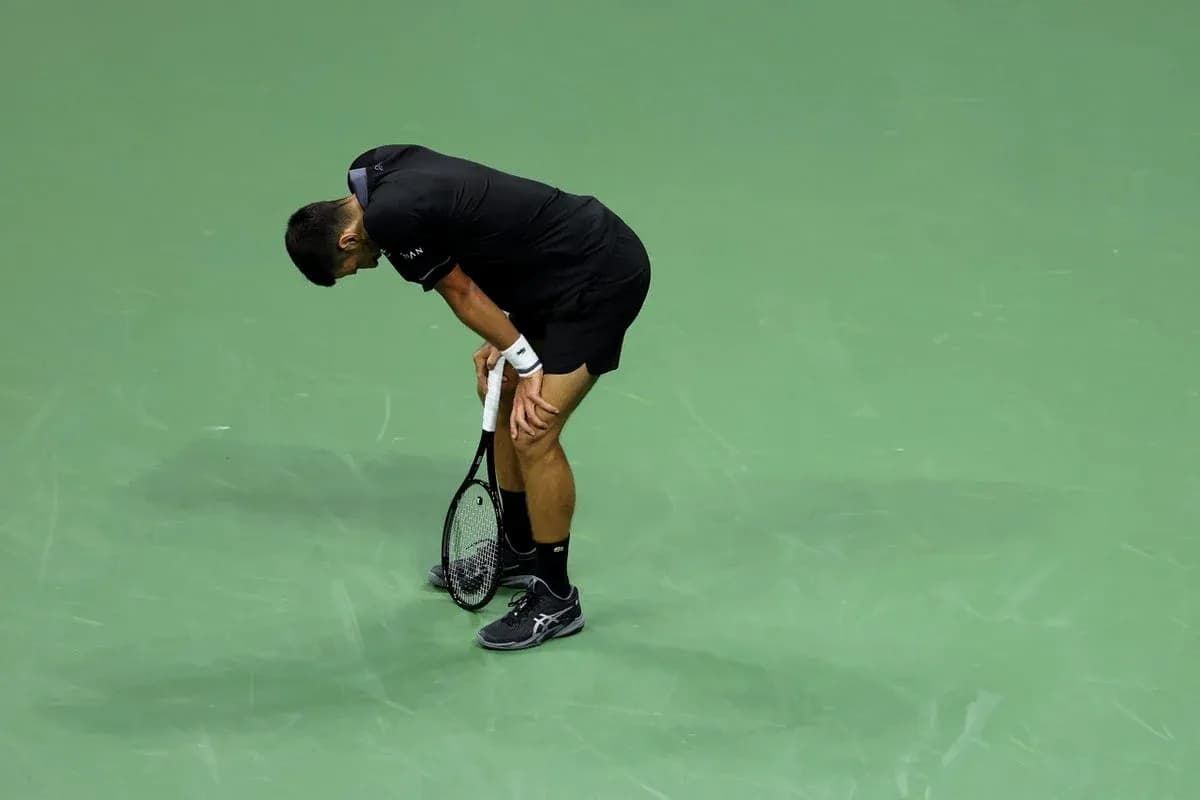 Jugador de tenis agachado con raqueta en la mano