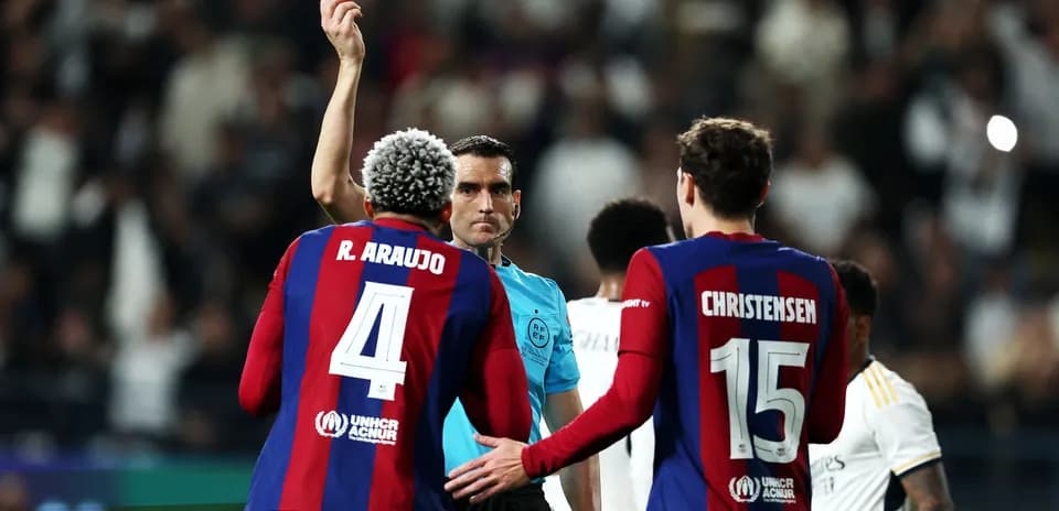 Árbitro mostrando tarjeta amarilla a jugador del Barcelona