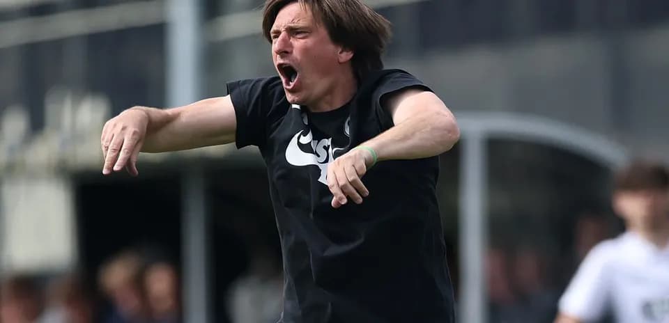 Entrenador gesticulando durante un partido de fútbol