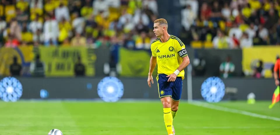Jugador caminando con balón en campo de fútbol