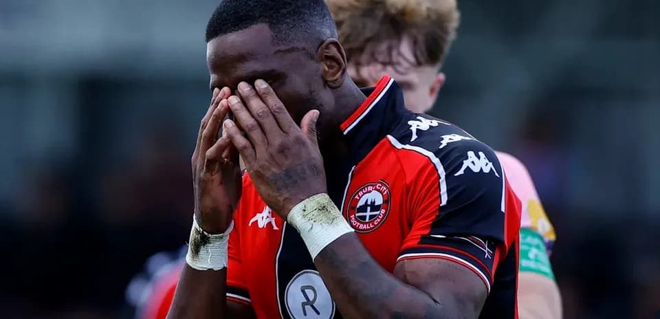 Jugador con camiseta de Truro City cubriendo su rostro