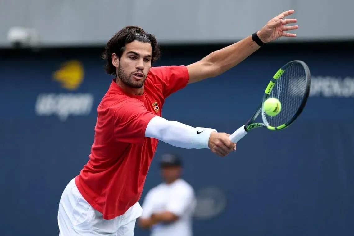 Jugador de tenis golpeando una pelota en la cancha Jugador de tenis golpeando una pelota en la cancha