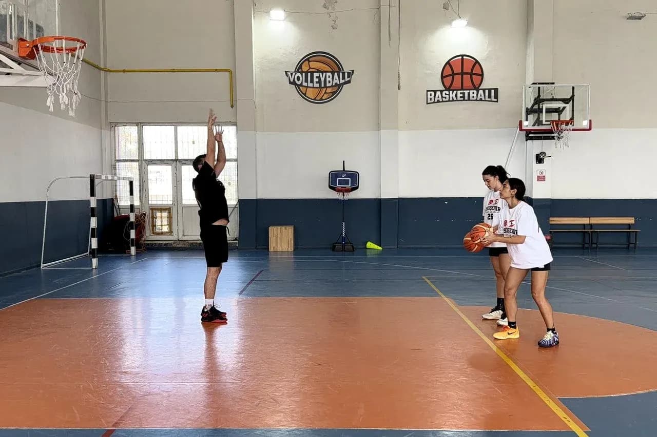 Entrenador enseñando tiro a dos jugadoras de baloncesto Entrenador enseñando tiro a dos jugadoras de baloncesto