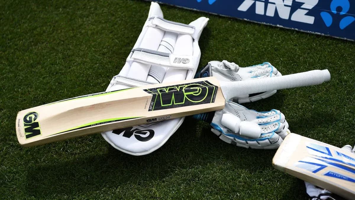 Bate de cricket y guantes sobre césped Bate de cricket y guantes sobre césped