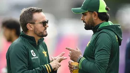 Entrenador y jugador conversando en campo de cricket Entrenador y jugador conversando en campo de cricket