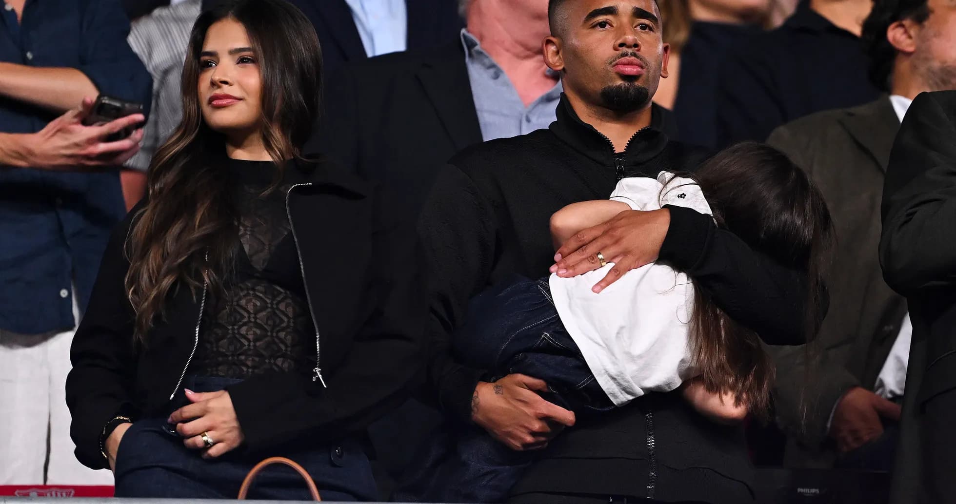 Pareja con niña en evento deportivo de pie Pareja con niña en evento deportivo de pie