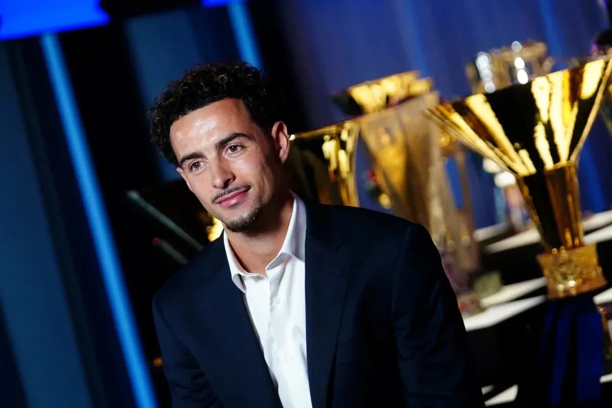 Jugador posando frente a trofeos en evento Jugador posando frente a trofeos en evento