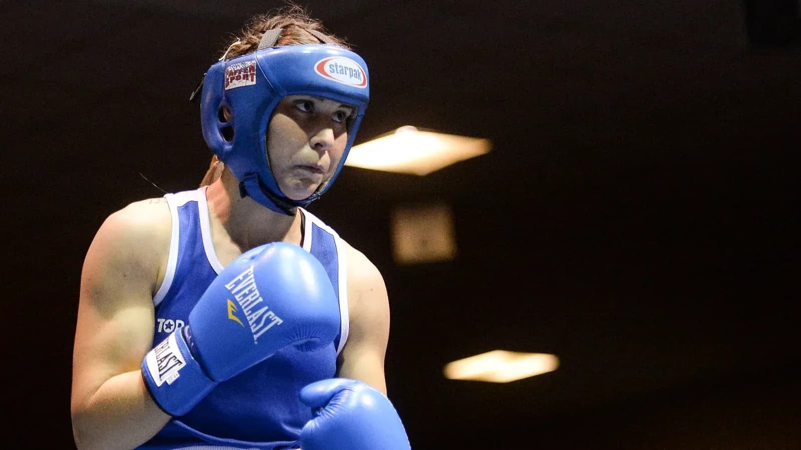 Boxeadora con guantes azules preparándose para pelear Boxeadora con guantes azules preparándose para pelear