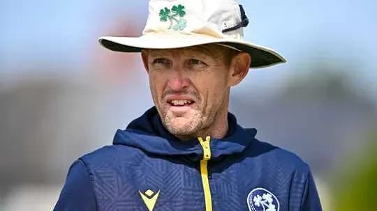 Entrenador de cricket con sombrero observando el campo Entrenador de cricket con sombrero observando el campo