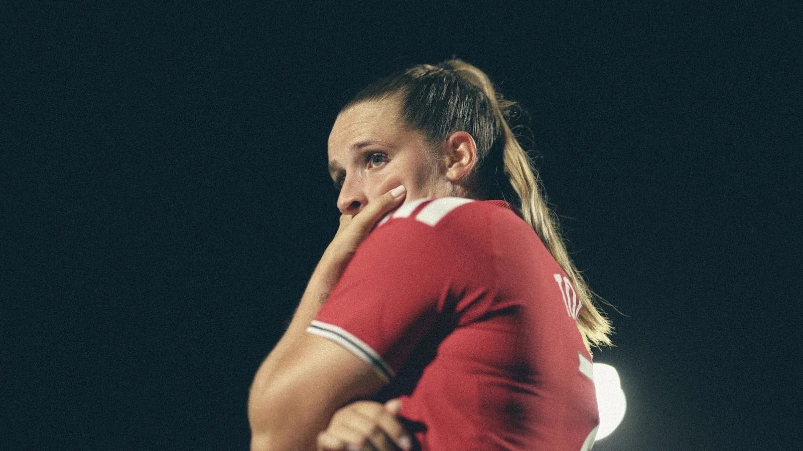 Jugadora con camiseta roja pensativa en el campo Jugadora con camiseta roja pensativa en el campo