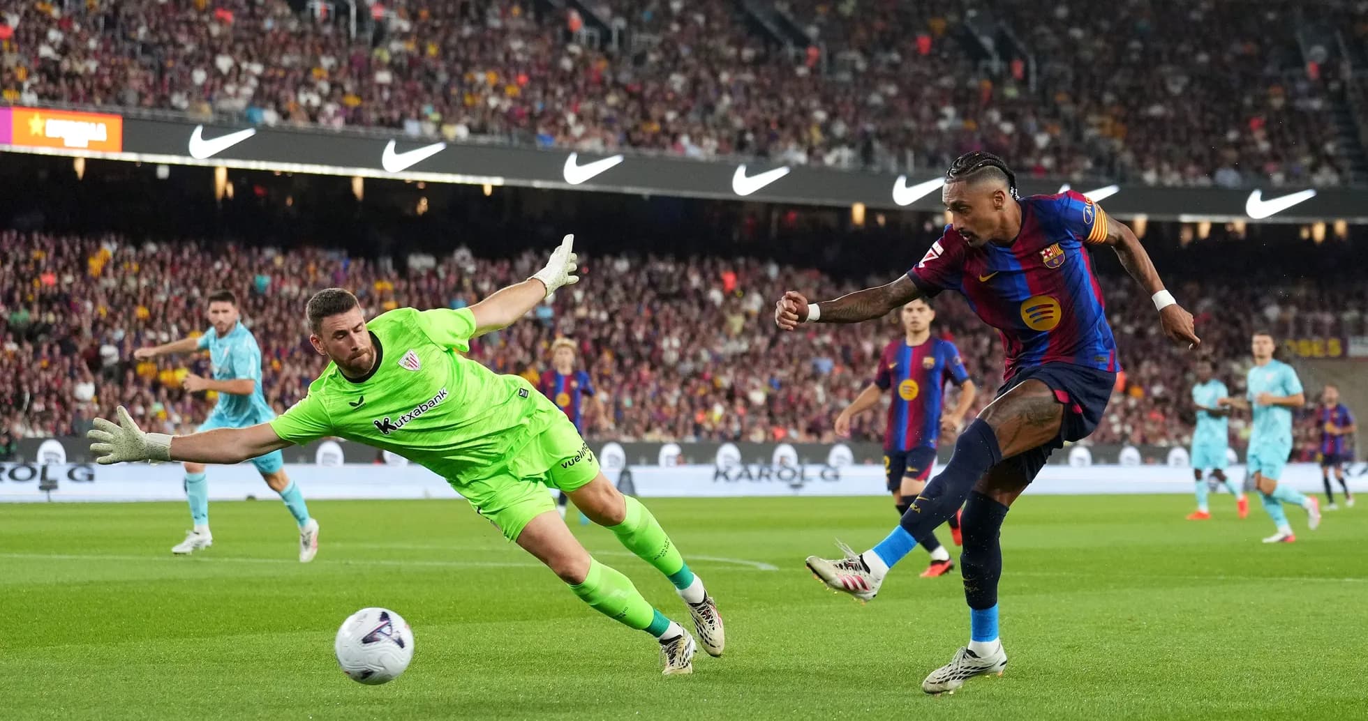 Jugador de Barcelona disparando mientras el portero intenta detenerlo Jugador de Barcelona disparando mientras el portero intenta detenerlo