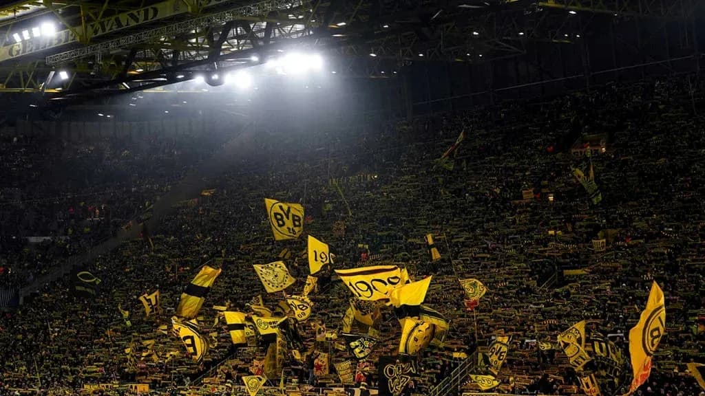 Aficionados de Borussia Dortmund agitando banderas en el estadio Aficionados de Borussia Dortmund agitando banderas en el estadio